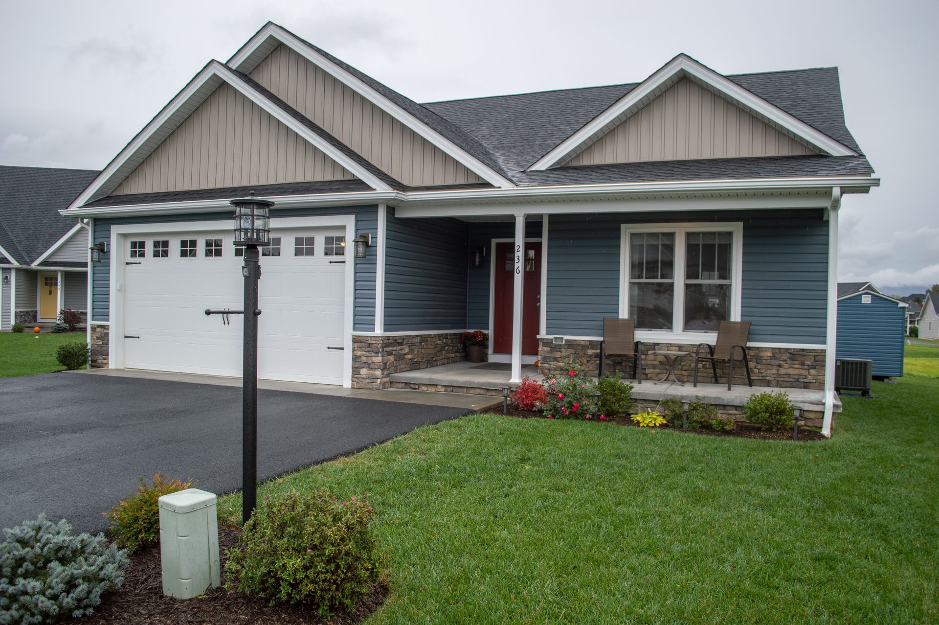 A blue house with a white garage door and a porch.