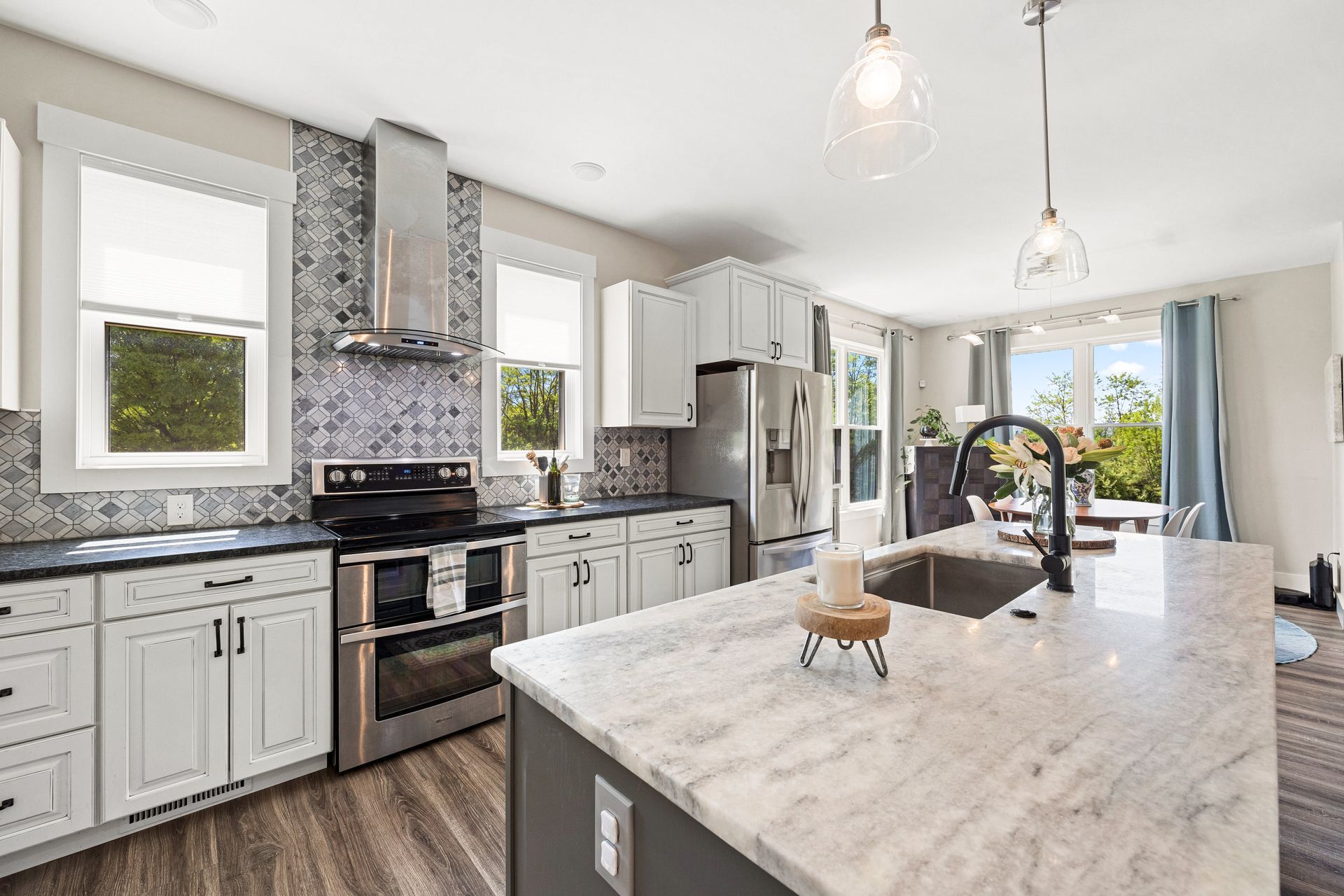 A kitchen with white cabinets , stainless steel appliances , granite counter tops and a large island.