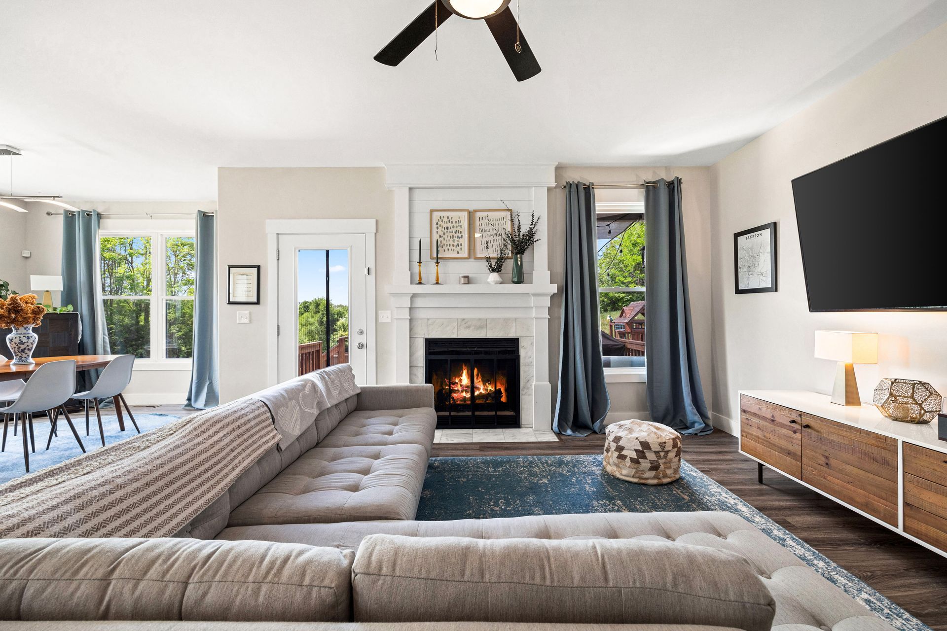 A living room with a couch , fireplace , television and ceiling fan.