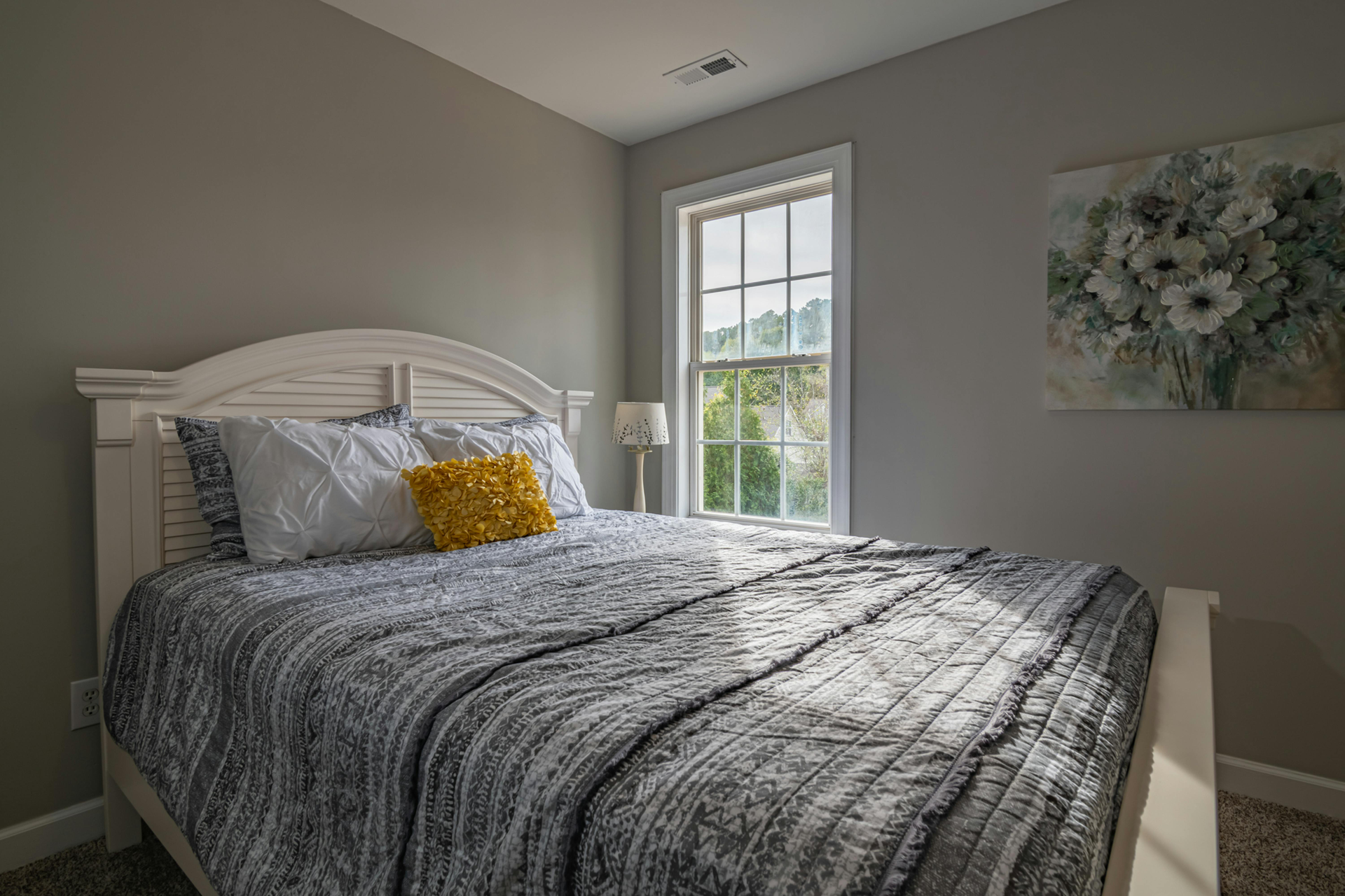 A bedroom with a bed , a window and a painting on the wall.