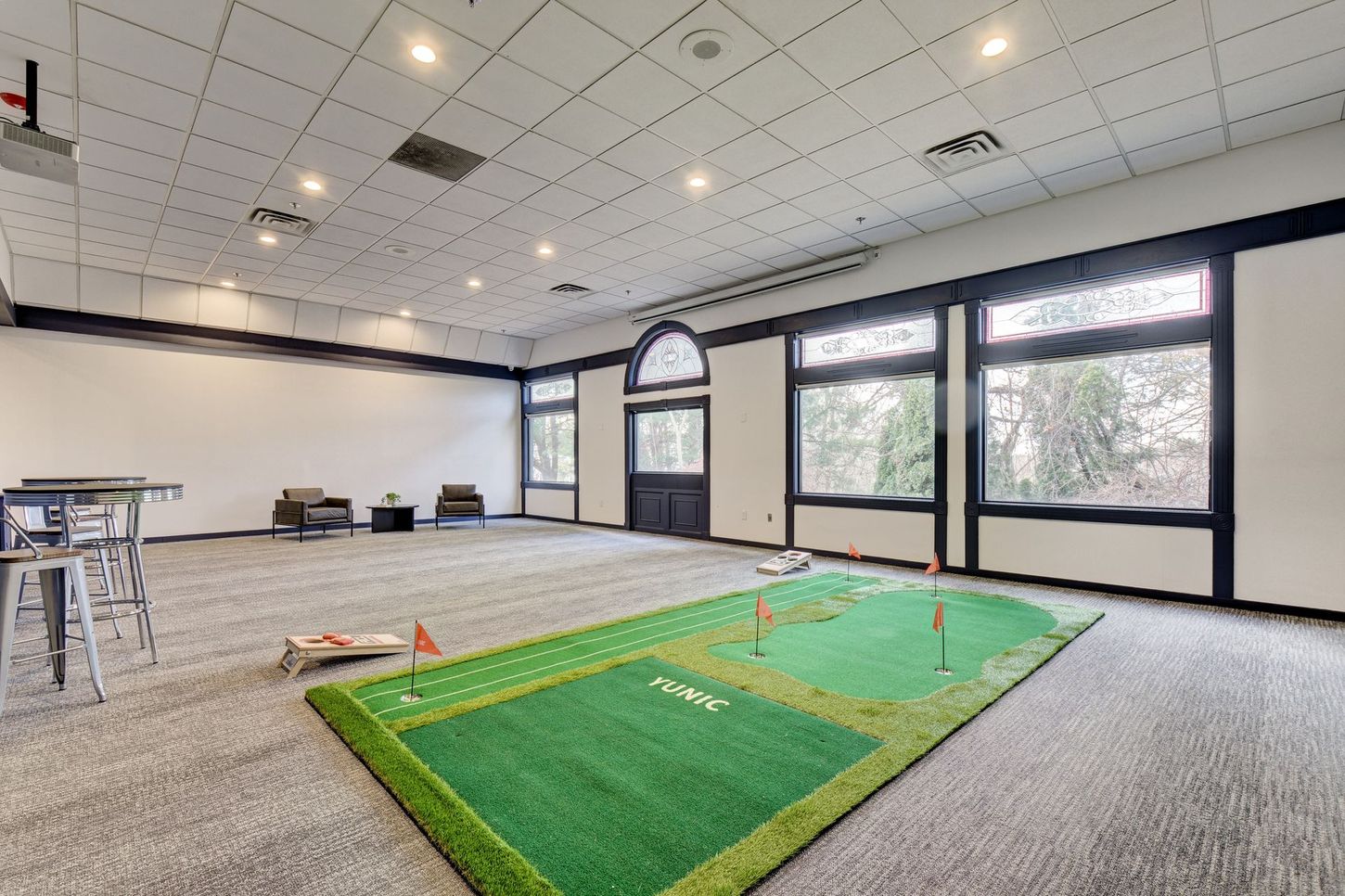 Indoor room with putting green, bar, and large windows.