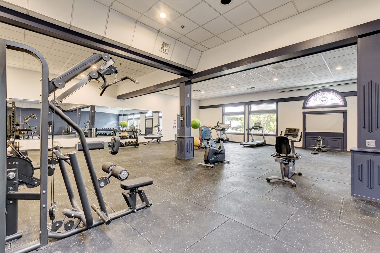Gym with various exercise machines and weights on a black rubber floor.