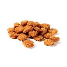 Una pila di bocconcini di pollo fritti su uno sfondo bianco.