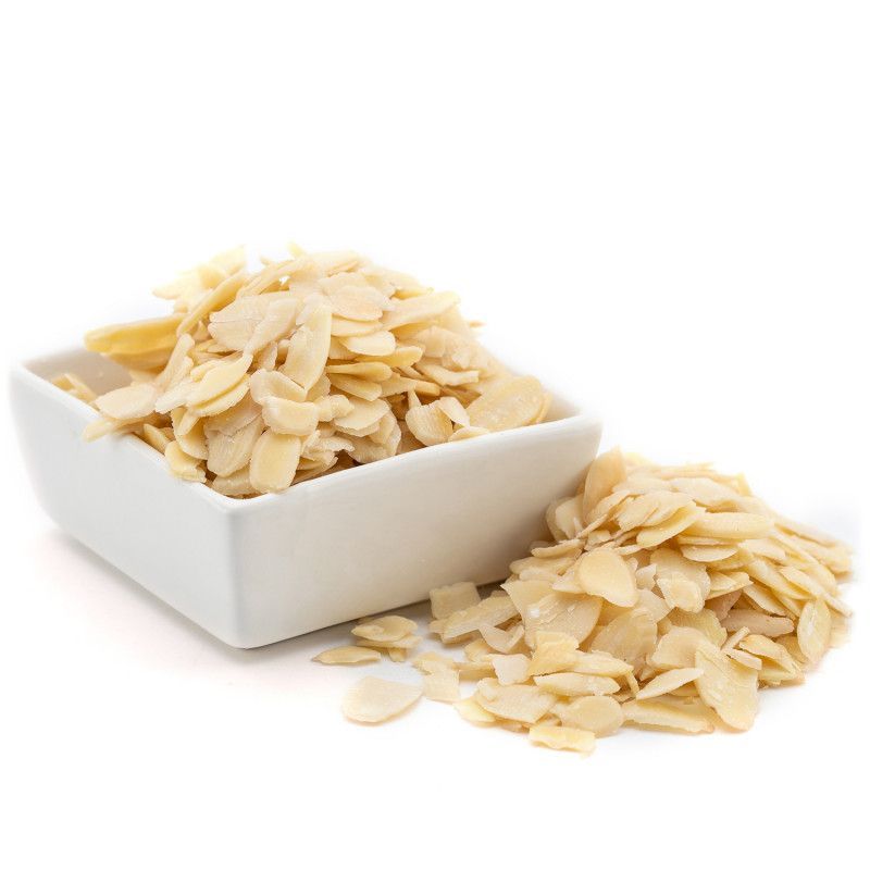 Una ciotola bianca piena di mandorle affettate su uno sfondo bianco.