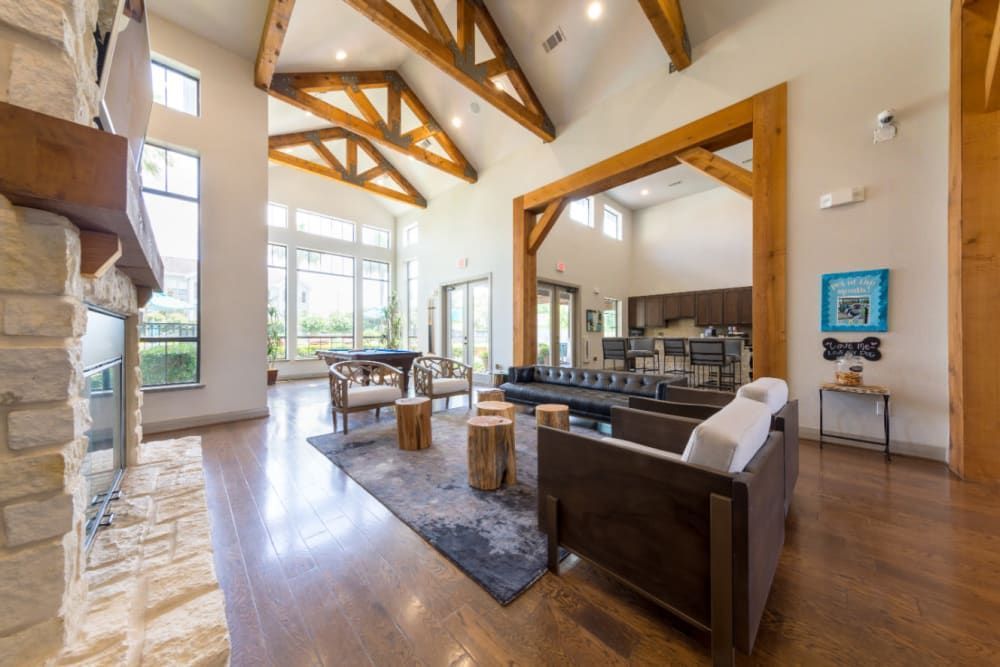 High-ceiling clubhouse filled with furniture and a fireplace at Marquis at Sugar Land in Sugar Land, TX.