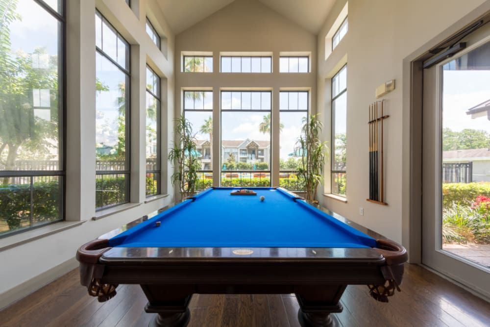 A pool table in the clubhouse with lots of windows at Marquis at Sugar Land in Sugar Land, TX.