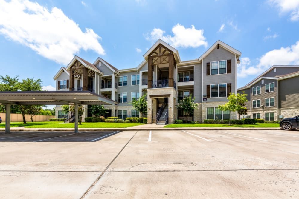 Apartment building exterior view with a car parked in front of it at Marquis at Sugar Land in Sugar Land, TX.