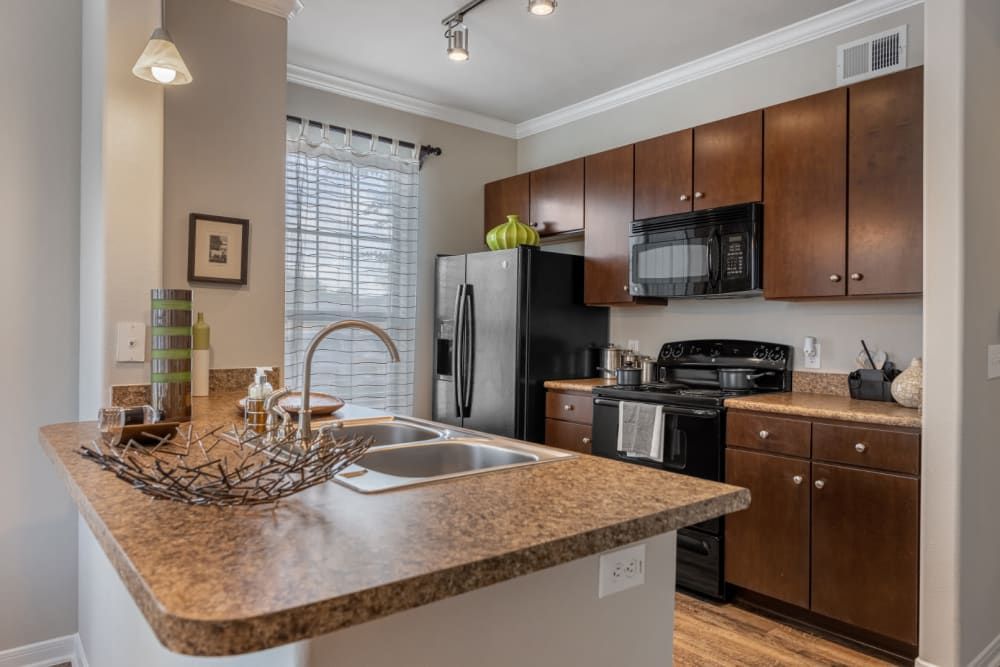 Apartment kitchen with granite counter tops, stainless steel appliances, and wooden cabinets at Marquis at Sugar Land in Sugar Land, TX.