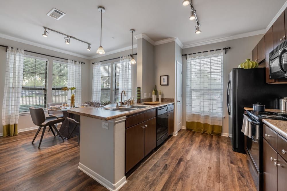 Apartment kitchen with hardwood floors, stainless steel appliances, and a large island at Marquis at Sugar Land in Sugar Land, TX.