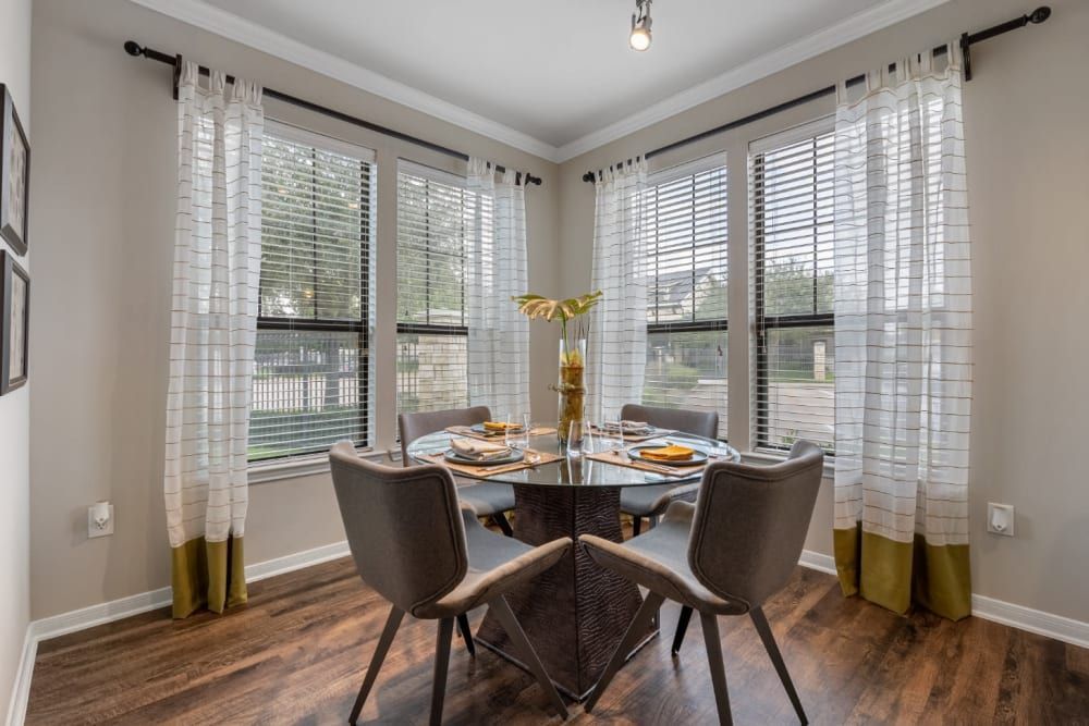 Apartment dining room with a table and chairs and lots of windows at Marquis at Sugar Land in Sugar Land, TX.
