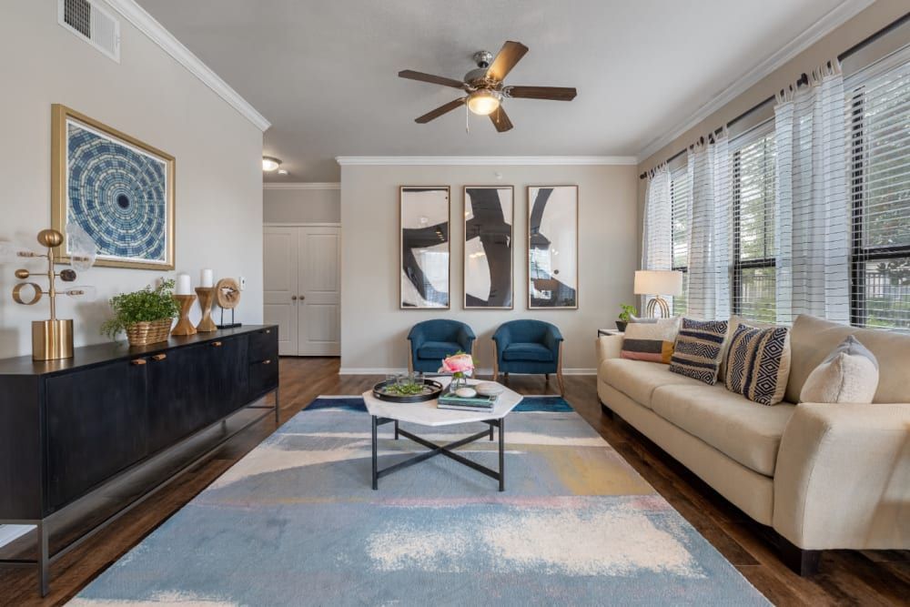 Apartment living room with a couch, coffee table, chairs, and a ceiling fan at Marquis at Sugar Land in Sugar Land, TX.