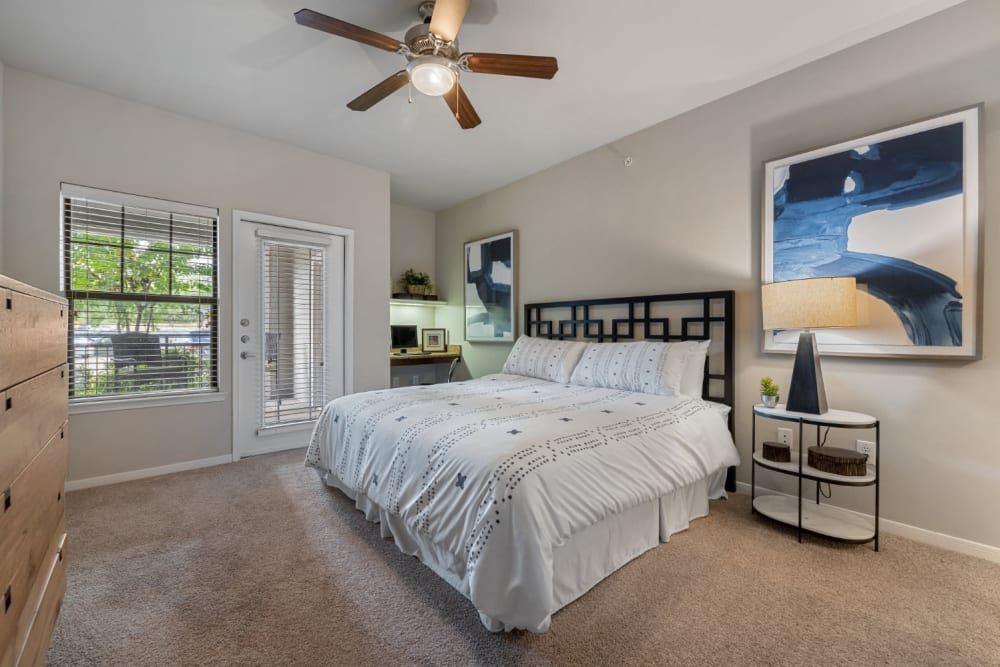 Apartment bedroom with a king-size bed, a ceiling fan, a dresser, and a painting on the wall at Marquis at Sugar Land in Sugar Land, TX.