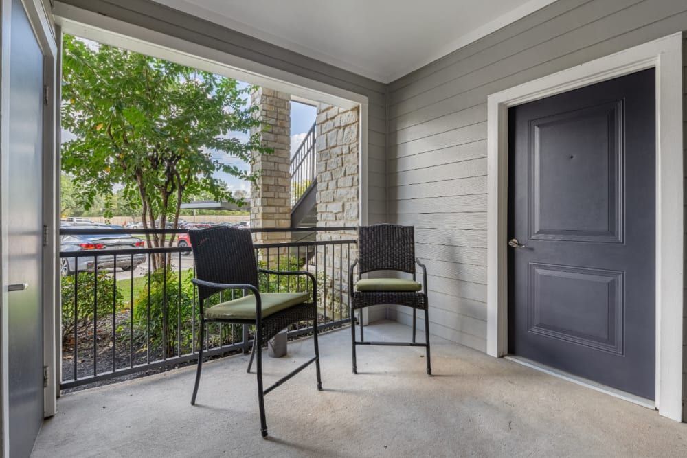 Apartment balcony with two chairs and a door to the apartment at Marquis at Sugar Land in Sugar Land, TX.