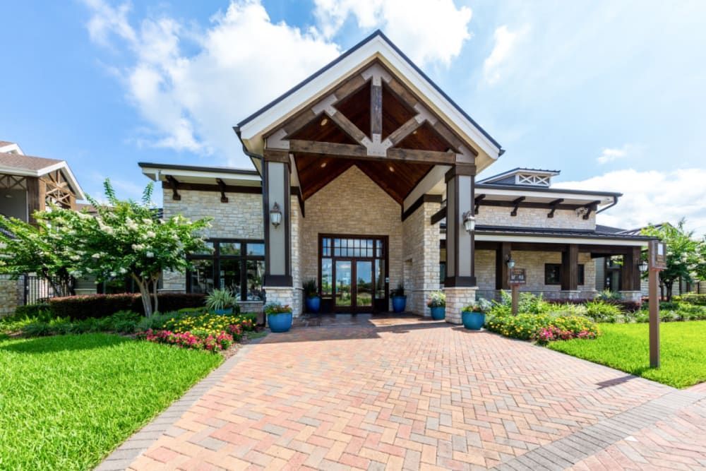 Exterior view of the leasing office building with a brick driveway leading to it at Marquis at Sugar Land in Sugar Land, TX.