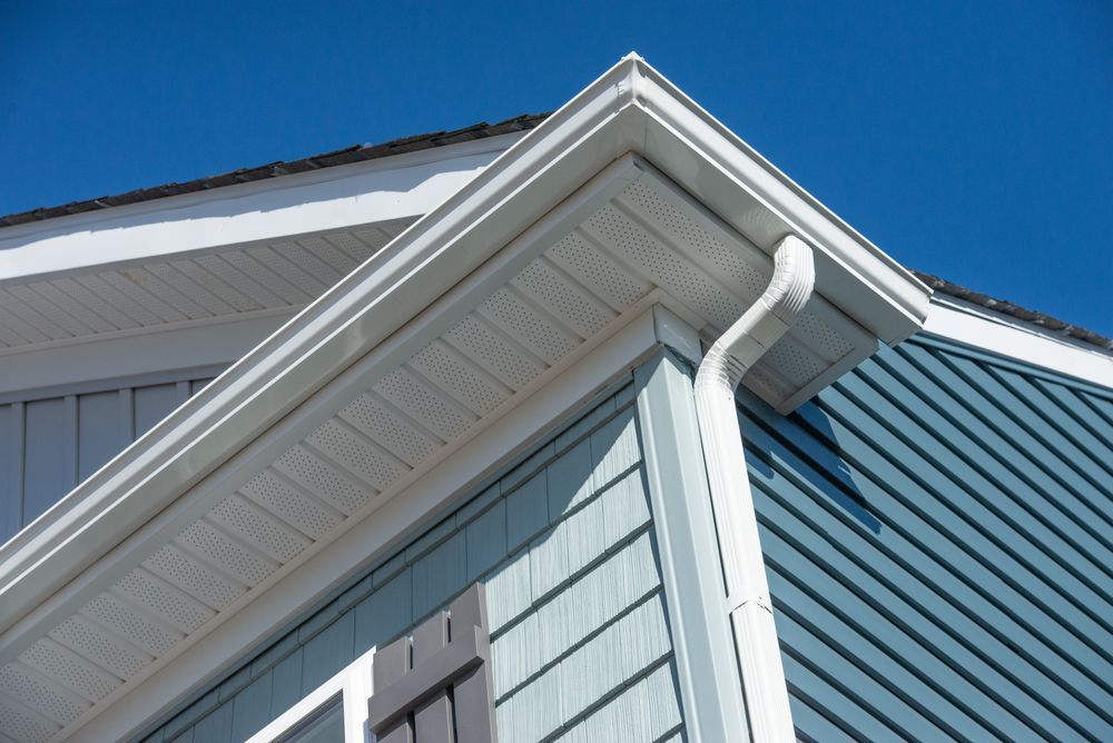 Corner of a House With White Trim, Gutters, and Blue Siding Against a Clear Sky — Ace1 Metal Roofing in Harrington, NSW