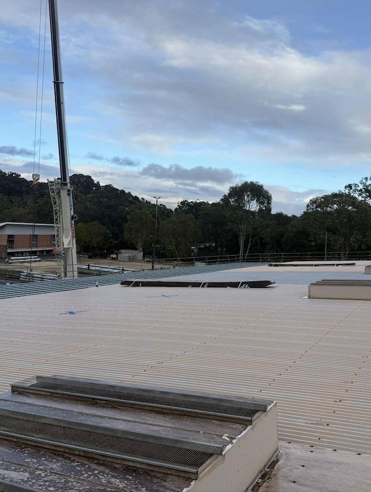Crane Over a Flat Roof With Patterned Panels, Construction Site Setting — Ace1 Metal Roofing in Kempsey, NSW
