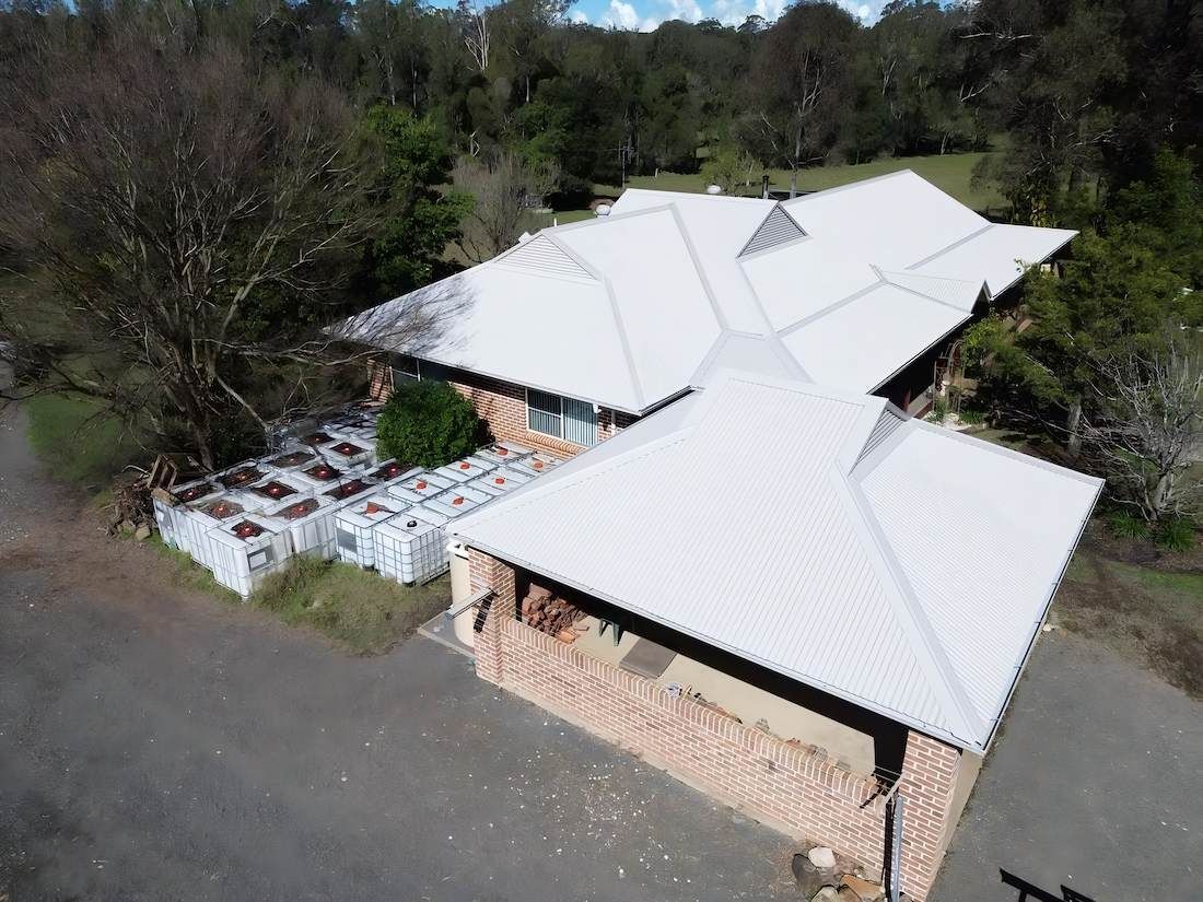 A Brick House With a White Roof Surrounded by Trees — Ace1 Metal Roofing in Port Macquarie, NSW