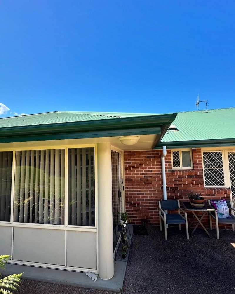 Exterior of a Brick Building With a Green Roof, Patio, and Clear Blue Sky — Ace1 Metal Roofing in Taree, NSW