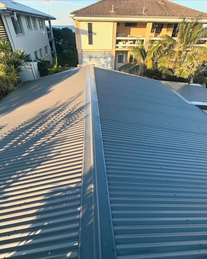 Grey Corrugated Metal Roof With Central Ridge and Adjacent Buildings — Ace1 Metal Roofing in Harrington, NSW