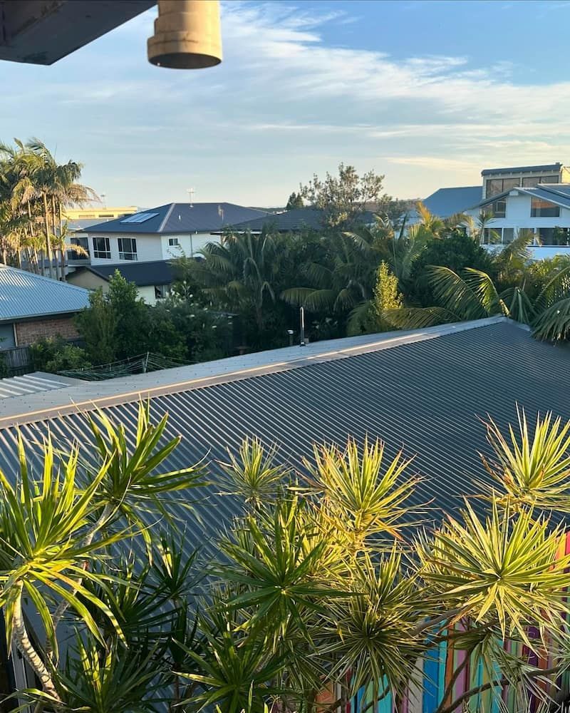 a Rooftop View of Houses and Lush Greenery Under a Bright Sky — Ace1 Metal Roofing in Taree, NSW