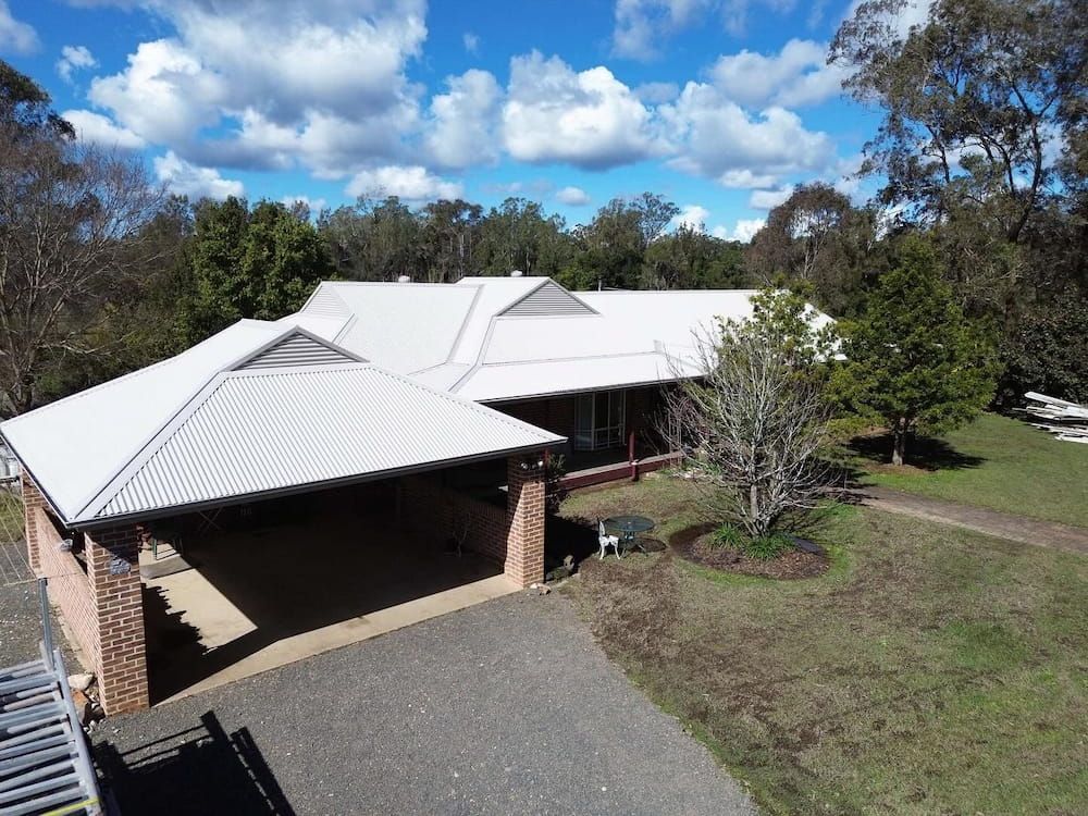 An Aerial View of a House With a White Roof and a Carport — Ace1 Metal Roofing in Taree, NSW