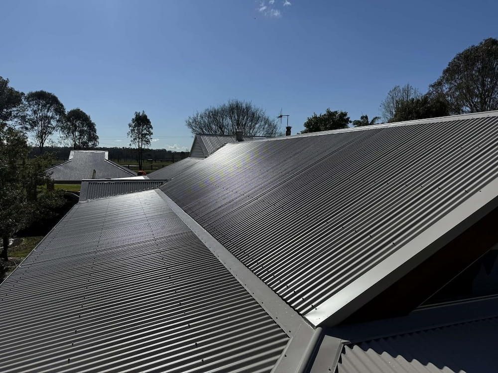 Grey Corrugated Metal Roof on a Sunny Day, With Trees in the Background — Ace1 Metal Roofing in Taree, NSW