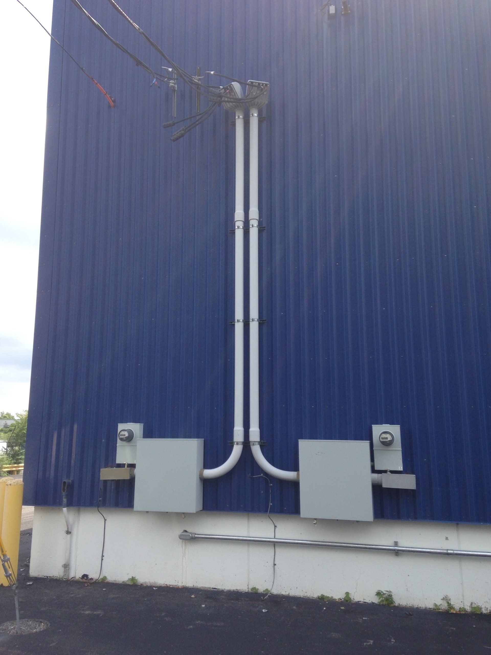 Blue building exterior with electrical conduit and two gray boxes. Power lines are visible at the top.