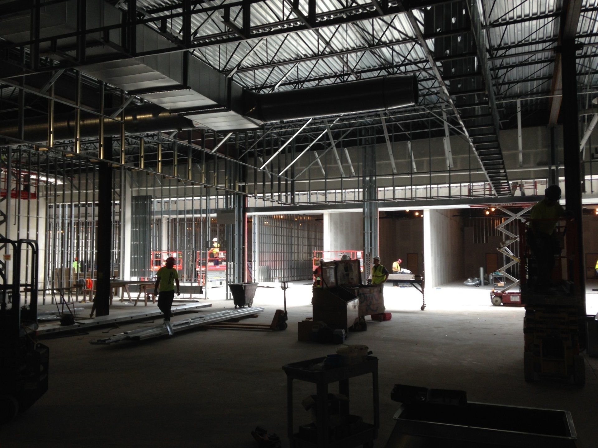 Interior construction site: Metal framework, unfinished walls, workers present.