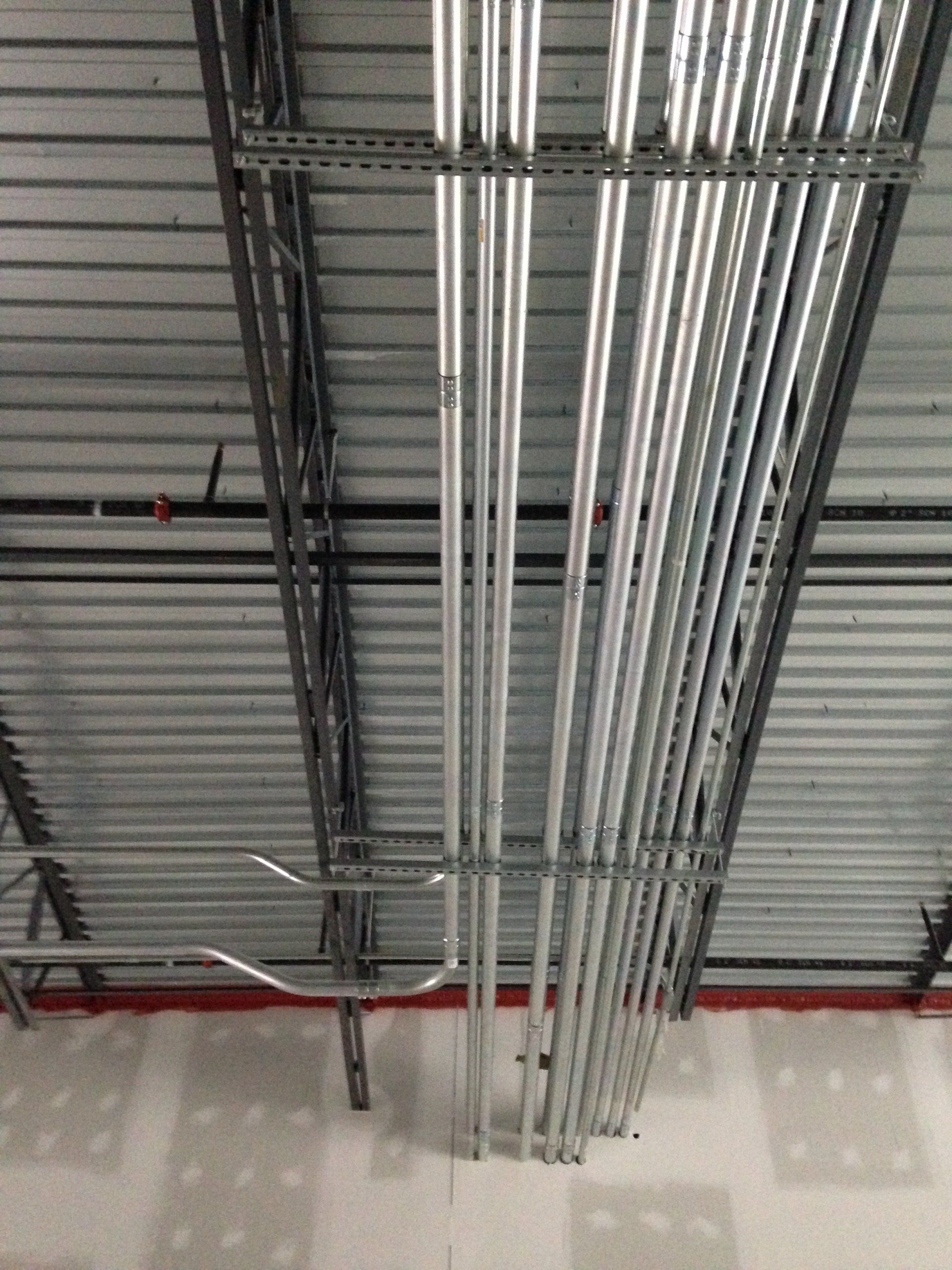 Metal conduits and support structures installed on a ceiling, likely for electrical wiring in a commercial building.