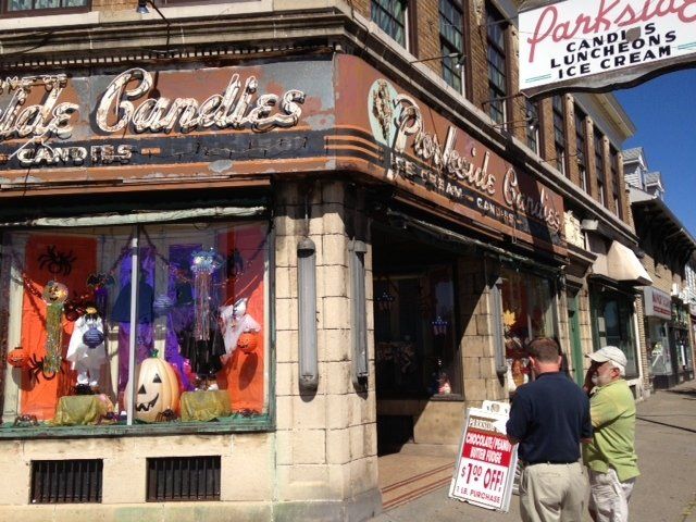 Parkside Candies storefront with Halloween decorations; two men stand outside.
