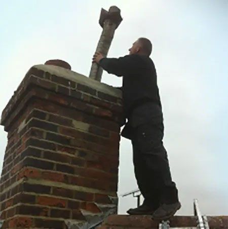 Man removing part of a chimney pipe