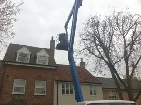 Blue cherry picker reaching a roof