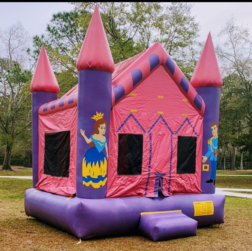 A purple and pink inflatable bounce house castle decorated with cartoon figures of a princess and a prince.