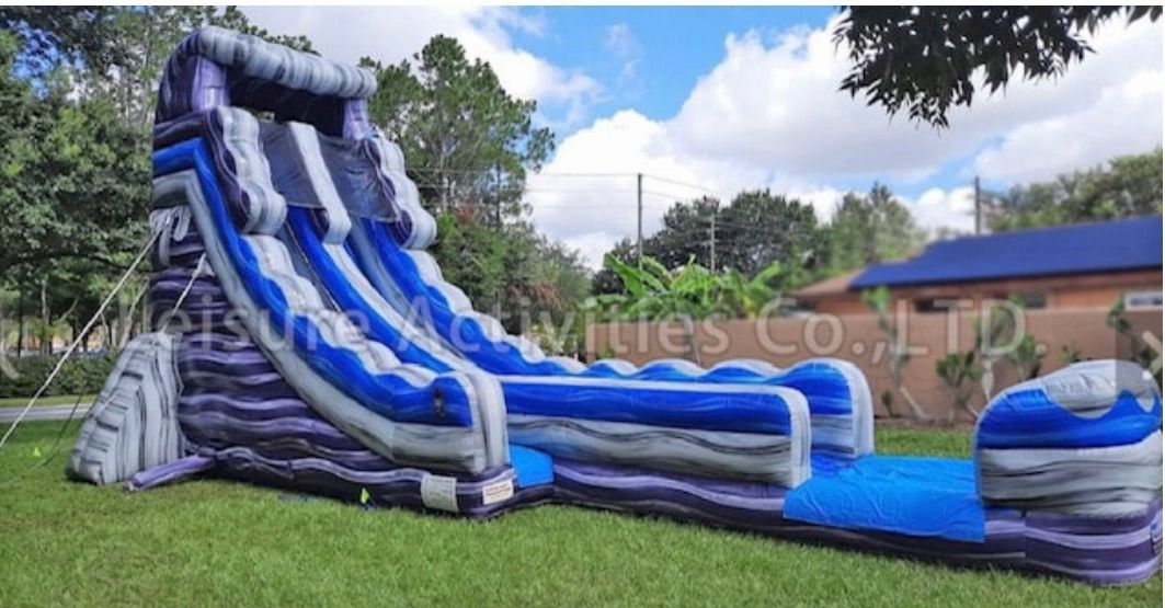 A large inflatable water slide with blue, grey, and purple marbling, set up on a grassy lawn.