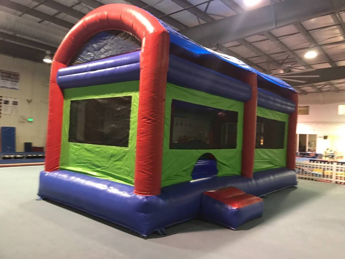 A red, blue, and green inflatable bounce house in an indoor recreational facility.