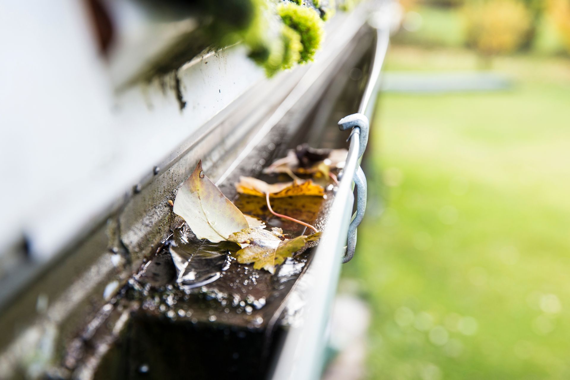 A man is fixing a gutter on the roof of a house.