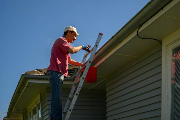 A man is standing on a ladder on the side of a house