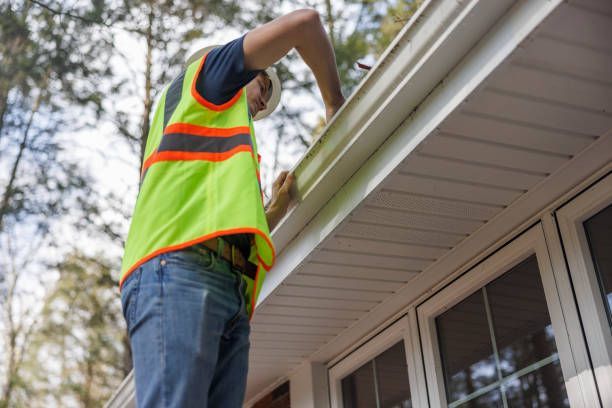 A man is working on a gutter on the side of a house.