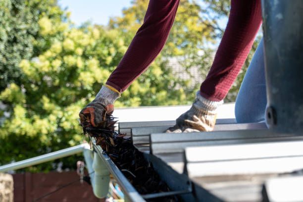 A person is cleaning a gutter on a roof.