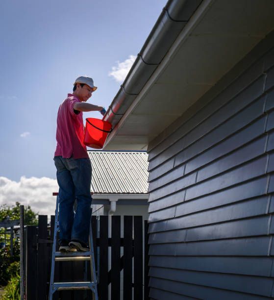 A man standing on a ladder holding a red bucket