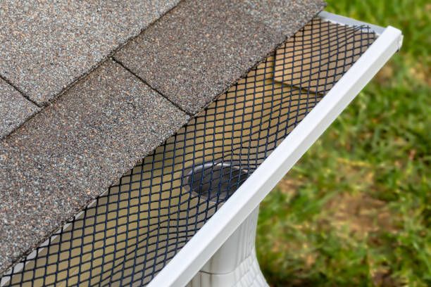 A close-up of a gutter with a mesh cover on it.