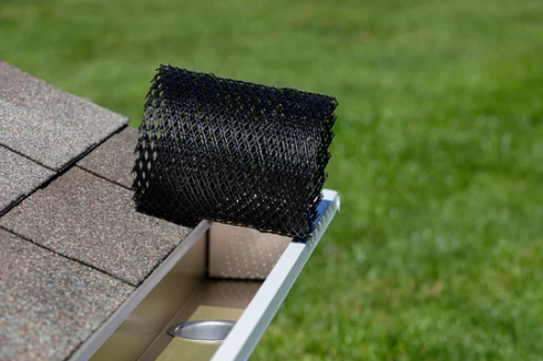 A roll of black mesh is sitting on top of a gutter.