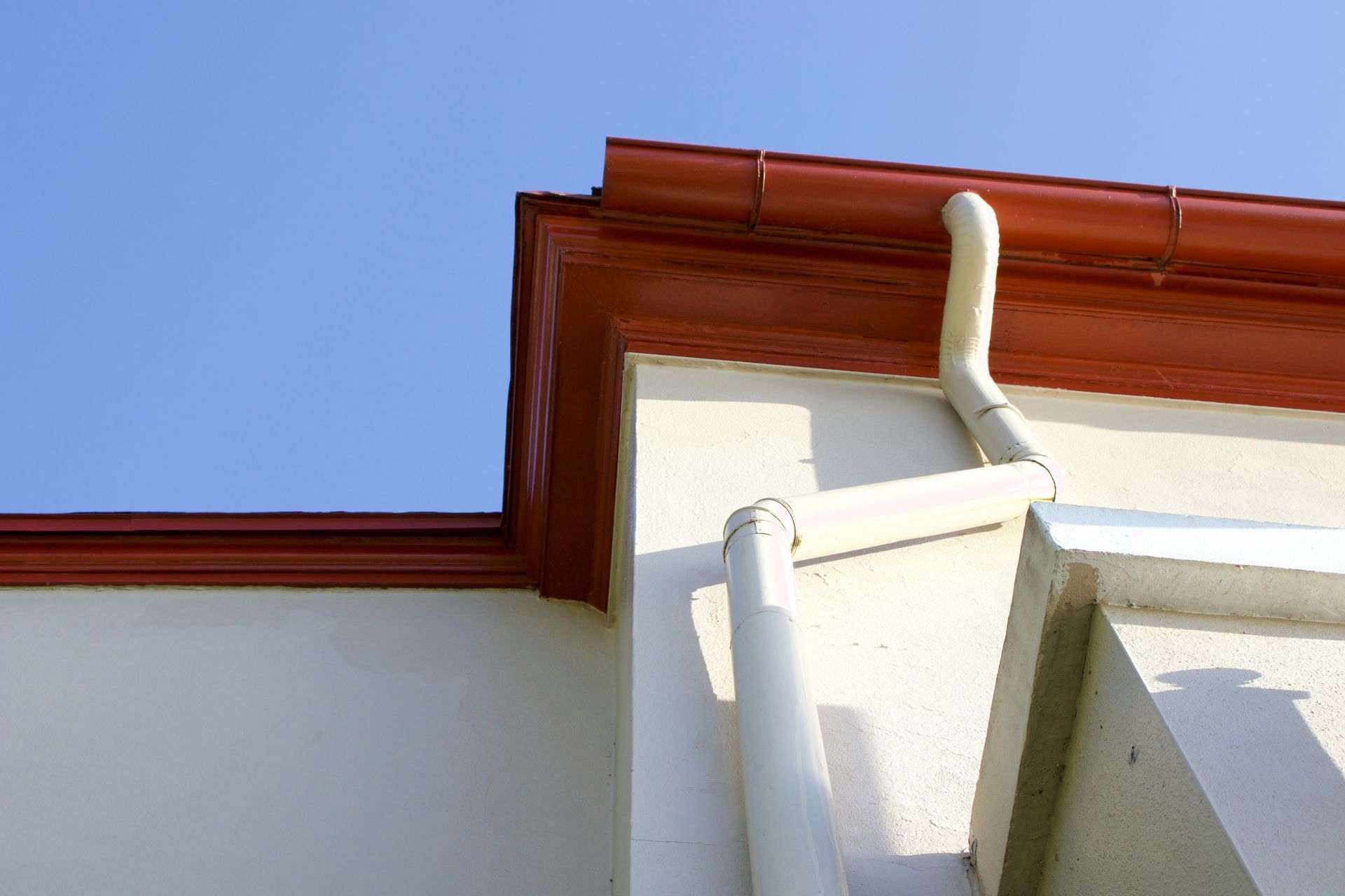 A gutter on the side of a building with a blue sky in the background