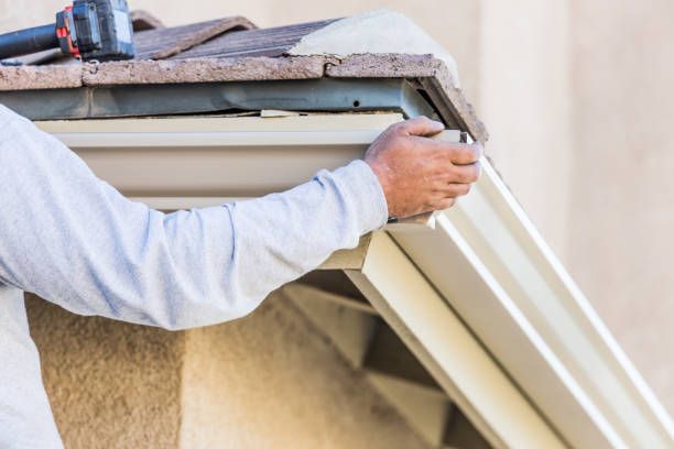 A man is installing a gutter on the side of a building.