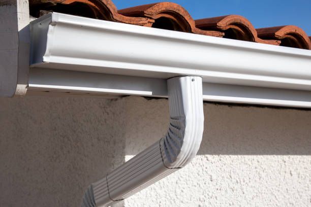 A white gutter is attached to the side of a house.