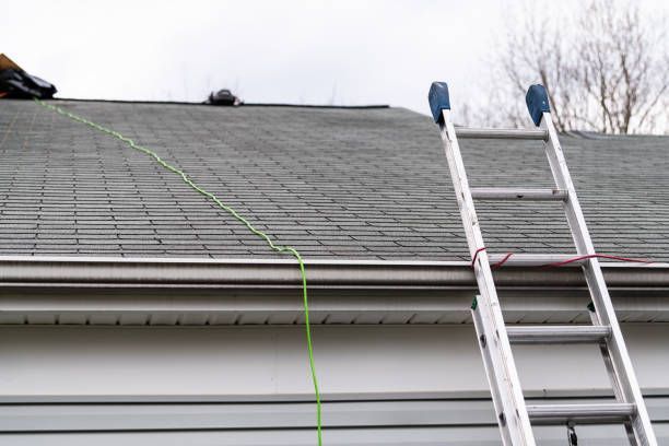 A man is working on the roof of a house with a ladder attached to it.