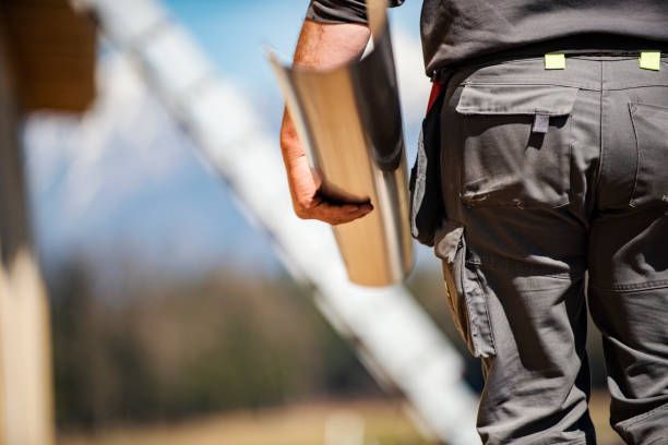 A man is carrying a gutter in his hand while walking.