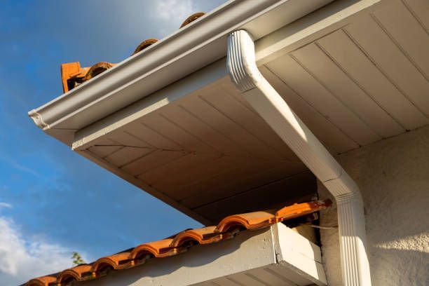 A white gutter on the side of a house with a tiled roof.