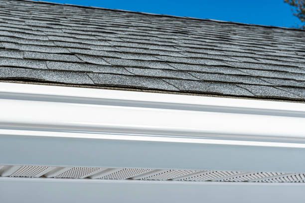 A close up of a gutter on a roof with a blue sky in the background.