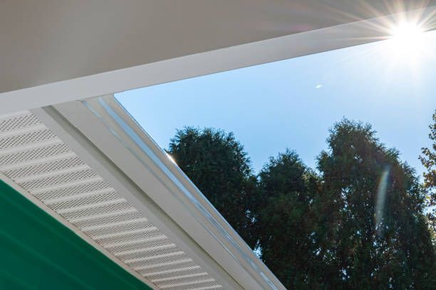 The sun is shining through the roof of a house with trees in the background.